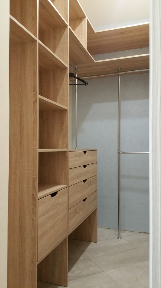 This is an example of a small walk-in wardrobe in Moscow with flat-panel cabinets, light wood cabinets, porcelain floors and grey floor.