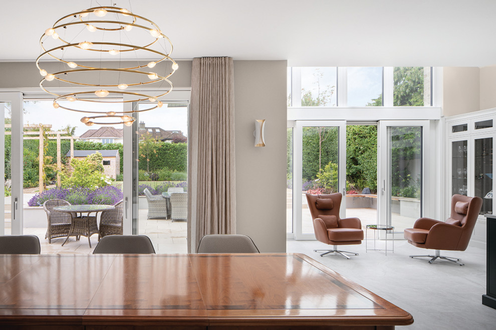 Photo of a large modern open plan dining in Dublin with beige walls, porcelain floors, a hanging fireplace, a plaster fireplace surround and grey floor.
