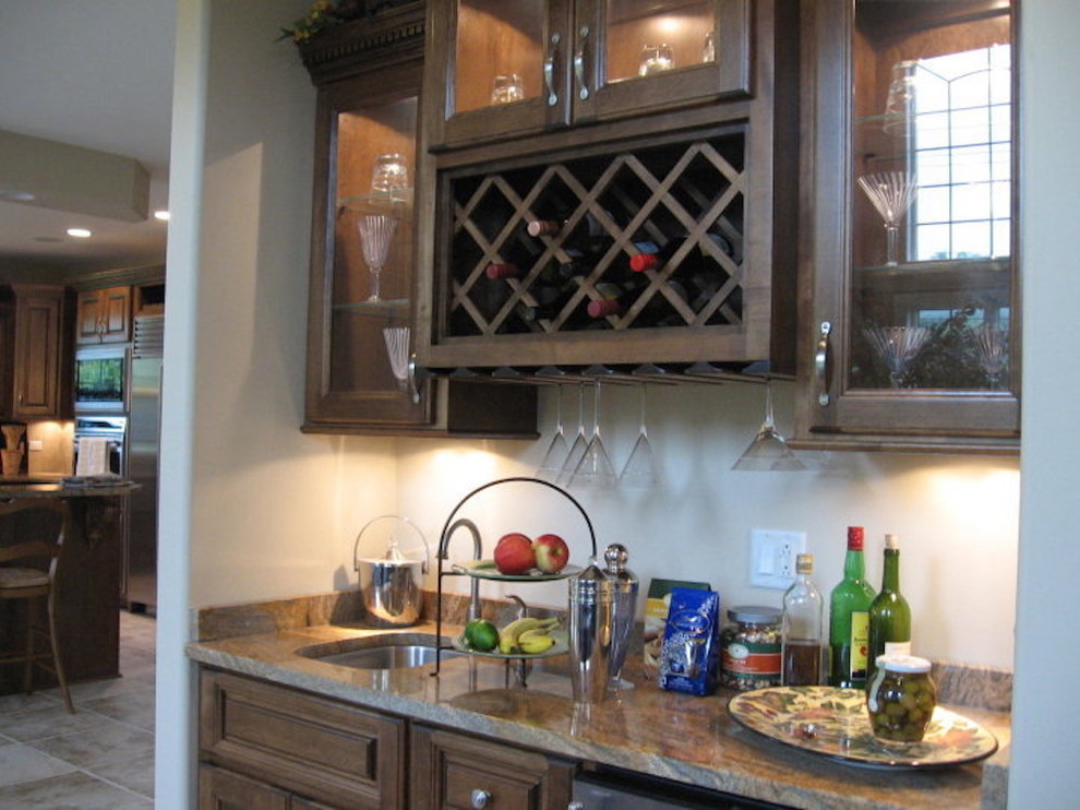 Example of a mid-sized transitional l-shaped ceramic tile and beige floor wet bar design in Chicago with an undermount sink, raised-panel cabinets, medium tone wood cabinets, marble countertops, beige backsplash, stainless steel appliances and an island