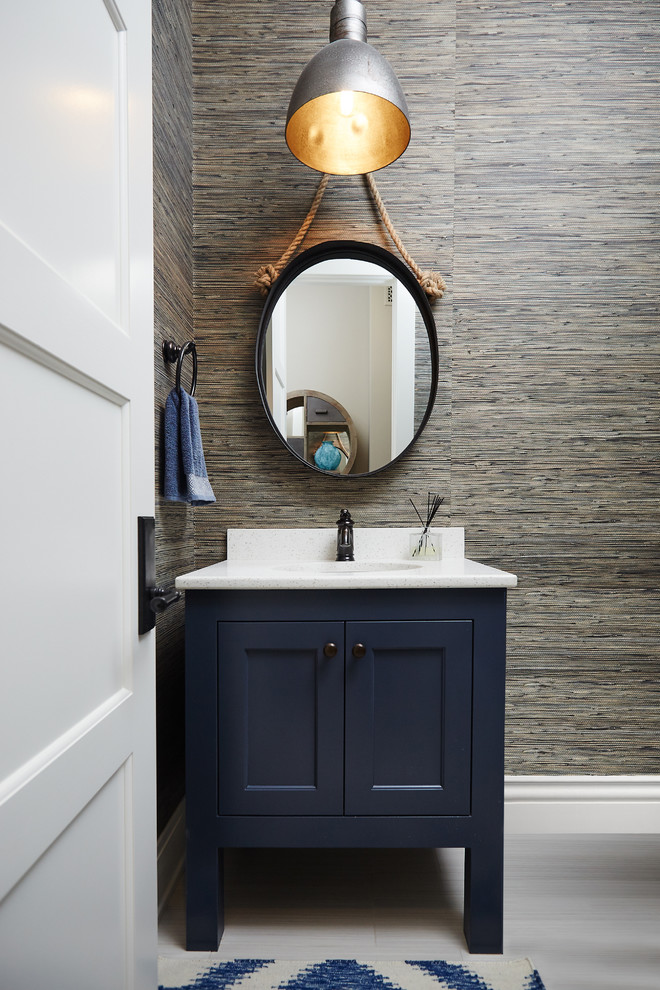 Photo of a beach style powder room in Grand Rapids with blue cabinets, multi-coloured walls, an undermount sink and recessed-panel cabinets.
