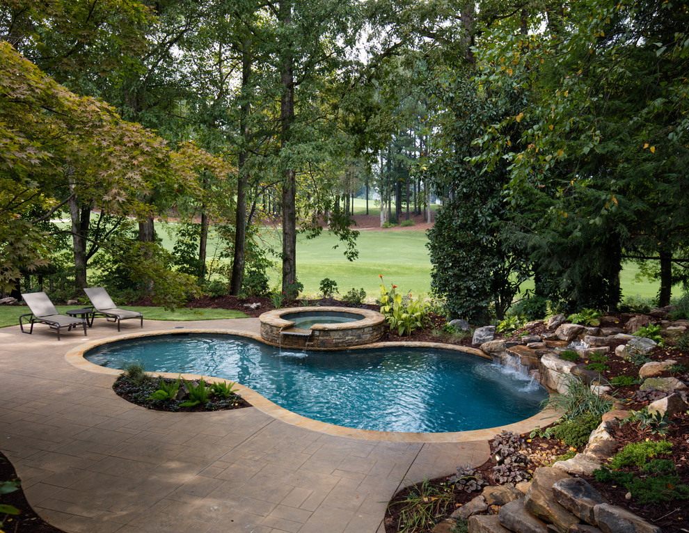 Photo of a mid-sized traditional backyard custom-shaped natural pool in Atlanta with a hot tub and natural stone pavers.
