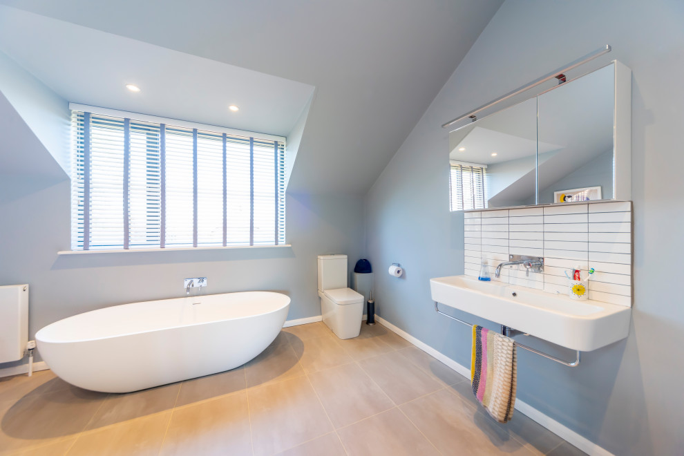 This is an example of a mid-sized contemporary kids bathroom in Buckinghamshire with a one-piece toilet, white tile, porcelain tile, blue walls, porcelain floors, an integrated sink and beige floor.