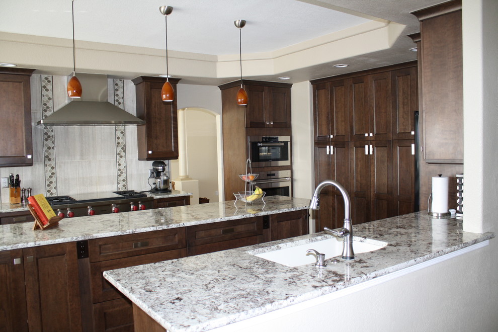 Example of a mid-sized transitional u-shaped dark wood floor eat-in kitchen design in Denver with an undermount sink, shaker cabinets, dark wood cabinets, granite countertops, gray backsplash, ceramic backsplash, stainless steel appliances and an island