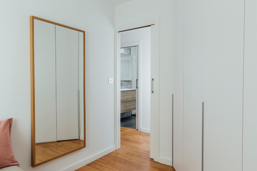 Photo of a mid-sized scandinavian women's built-in wardrobe in Other with flat-panel cabinets, white cabinets, medium hardwood floors and brown floor.