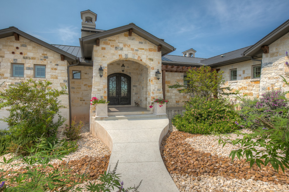 Photo of a large traditional two-storey brown house exterior in Austin with stone veneer, a gable roof and a metal roof.
