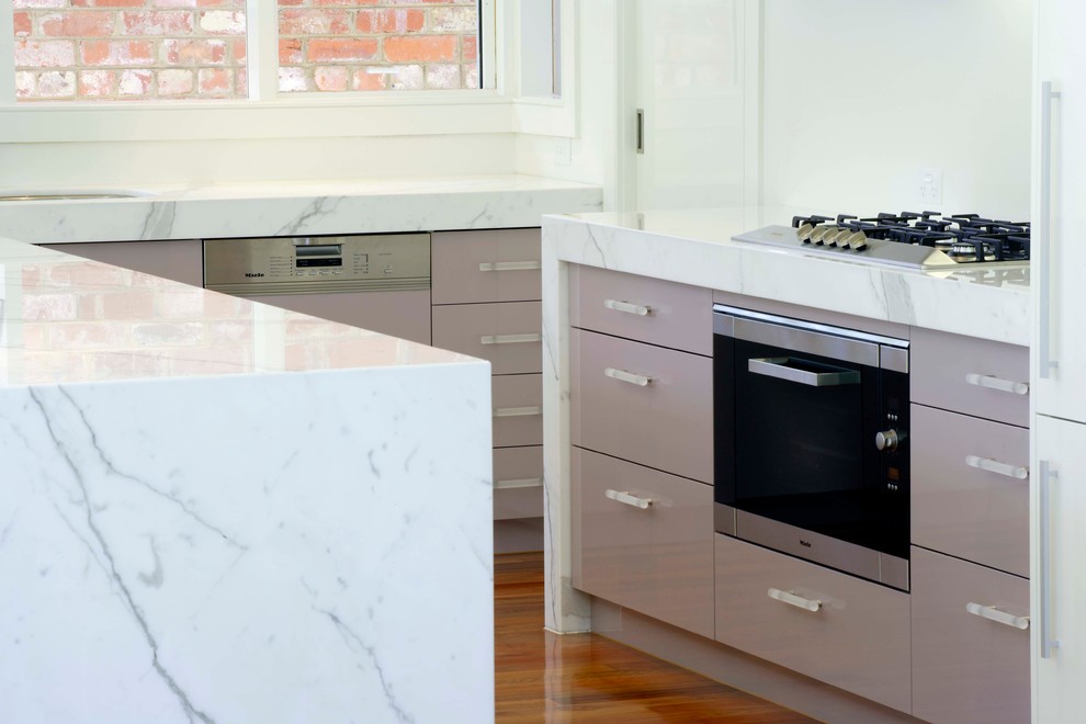 Large contemporary l-shaped kitchen pantry in Melbourne with an undermount sink, flat-panel cabinets, grey cabinets, marble benchtops, white splashback, glass sheet splashback, stainless steel appliances, with island and medium hardwood floors.