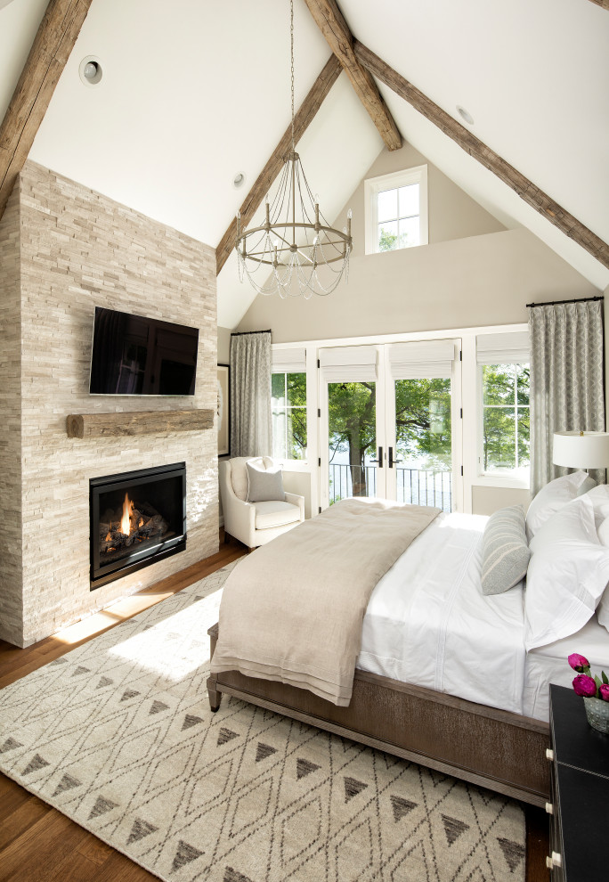 Inspiration for a mid-sized transitional master bedroom in Minneapolis with beige walls, medium hardwood floors, a standard fireplace, a stone fireplace surround and brown floor.