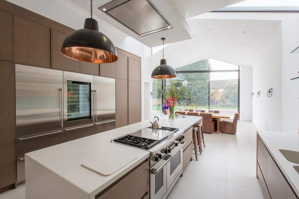 This is an example of a large contemporary galley open plan kitchen in London with an integrated sink, flat-panel cabinets, dark wood cabinets, quartzite benchtops, green splashback, glass sheet splashback, panelled appliances, ceramic floors, with island, white floor and white benchtop.