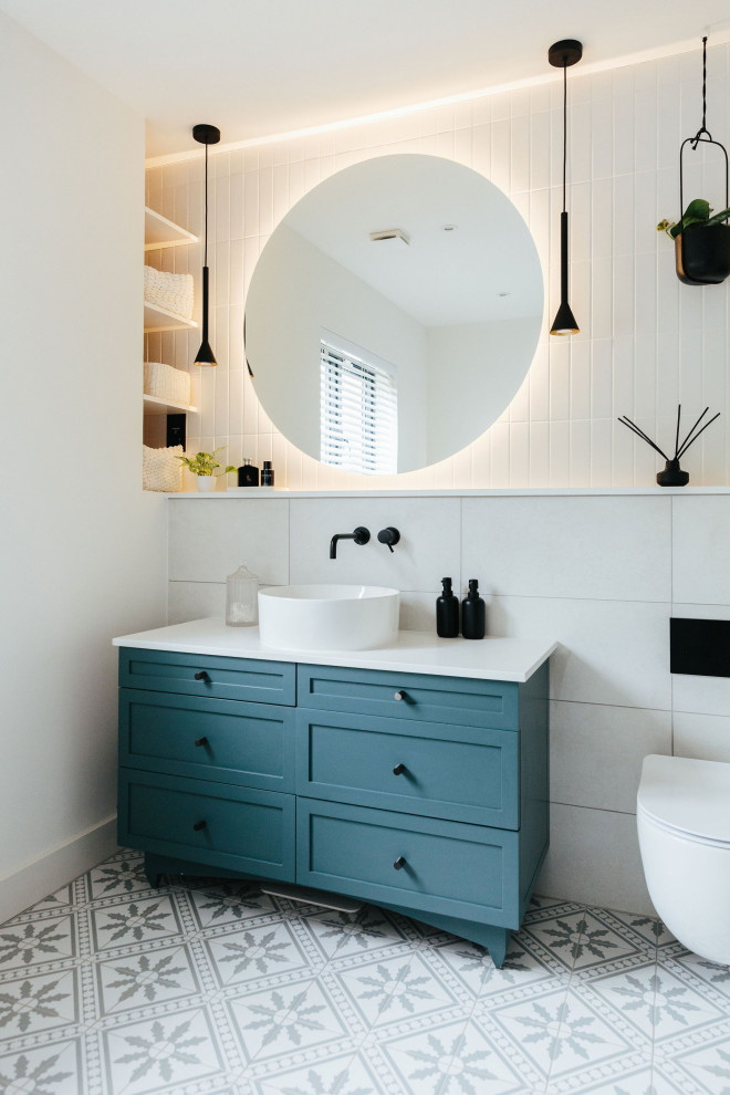 Design ideas for a mid-sized transitional kids bathroom in London with shaker cabinets, blue cabinets, a wall-mount toilet, white tile, mosaic tile floors, a drop-in sink, marble benchtops, blue floor, a hinged shower door, white benchtops, a single vanity, a built-in vanity and panelled walls.