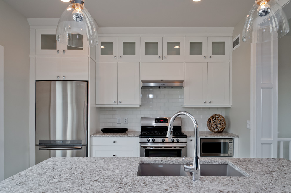 Inspiration for a mid-sized transitional eat-in kitchen in Calgary with an undermount sink, white cabinets, quartz benchtops, white splashback, subway tile splashback, stainless steel appliances, with island and dark hardwood floors.