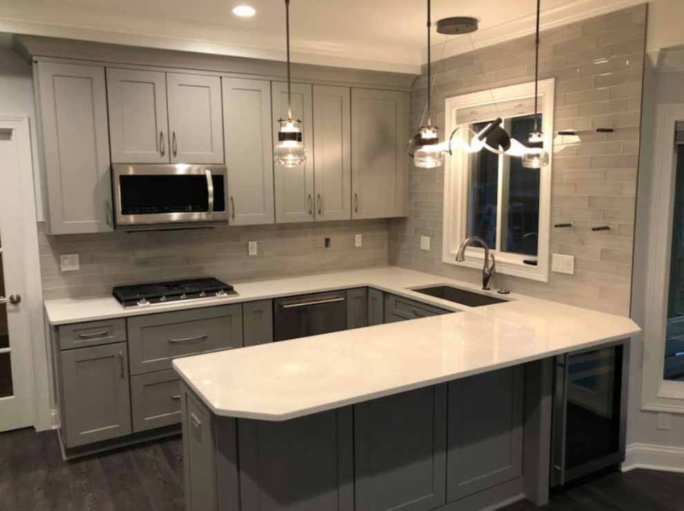 Kitchen - transitional u-shaped gray floor kitchen idea with an undermount sink, recessed-panel cabinets, gray cabinets, gray backsplash, stainless steel appliances and white countertops