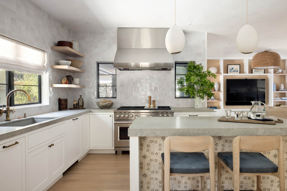 This is an example of a large transitional galley open plan kitchen in San Francisco with grey splashback, ceramic splashback, stainless steel appliances, light hardwood floors, with island, grey benchtop, an integrated sink, shaker cabinets, white cabinets, limestone benchtops and beige floor.