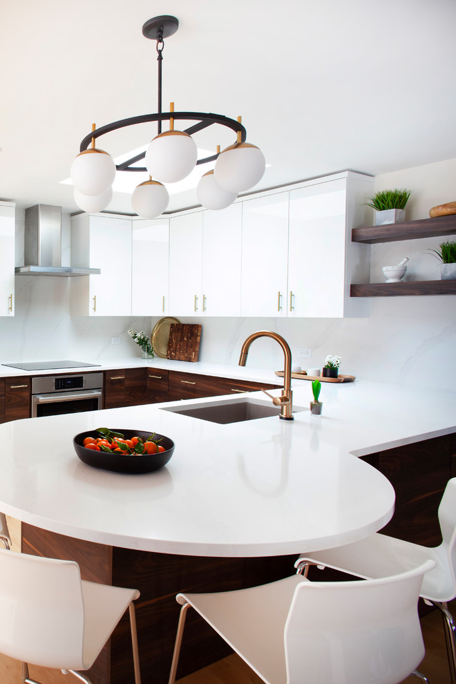 Photo of a mid-sized contemporary u-shaped eat-in kitchen in Chicago with a single-bowl sink, flat-panel cabinets, medium wood cabinets, quartz benchtops, white splashback, stainless steel appliances, light hardwood floors, a peninsula, brown floor and white benchtop.