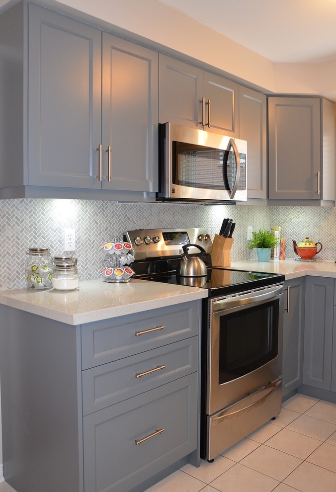 This is an example of a small transitional u-shaped eat-in kitchen in Toronto with an undermount sink, shaker cabinets, grey cabinets, quartz benchtops, multi-coloured splashback, stone tile splashback, stainless steel appliances, porcelain floors and no island.