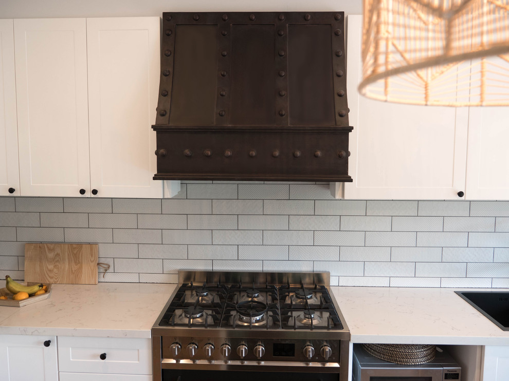 Industrial kitchen in Melbourne with beaded inset cabinets, white cabinets, marble benchtops, white splashback, subway tile splashback, black appliances and white benchtop.