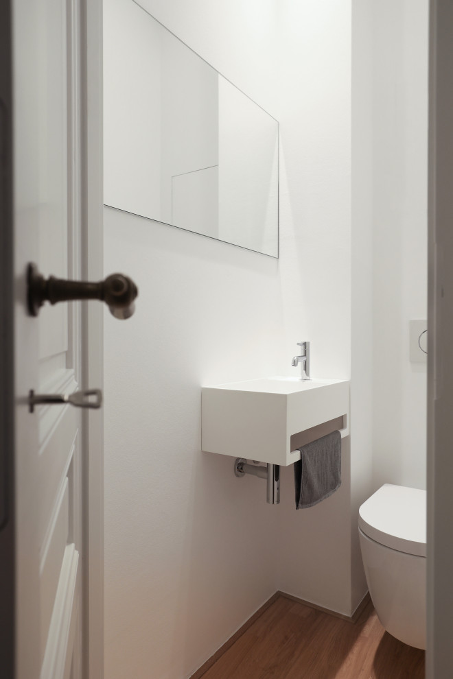 Cette image montre un grand WC et toilettes traditionnel avec un mur blanc et parquet clair.