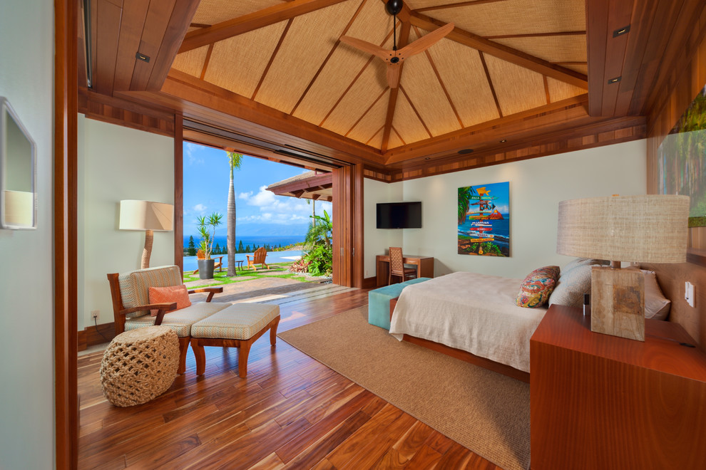 Large tropical master bedroom in Hawaii with green walls, medium hardwood floors and brown floor.