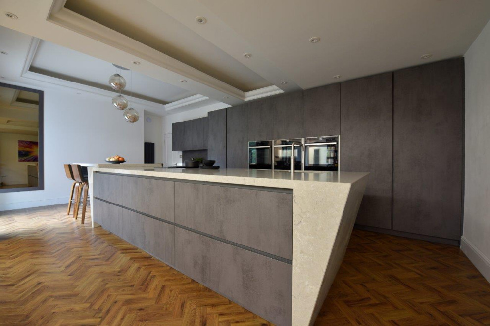 Foto di un grande cucina con isola centrale moderno con lavello sottopiano, ante lisce, ante grigie, top in quarzite, paraspruzzi grigio, elettrodomestici neri e top beige