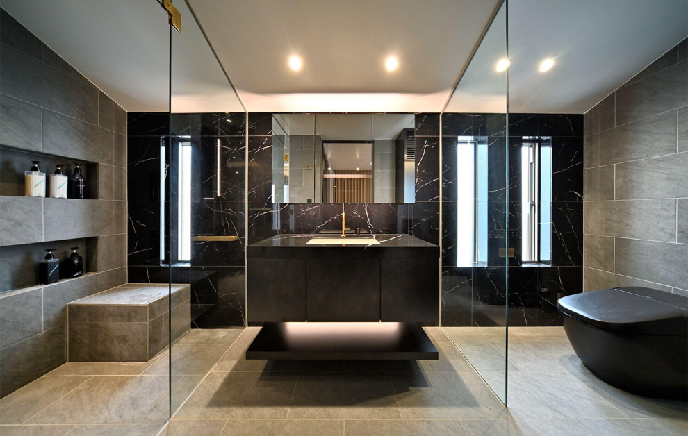 Medium sized modern grey and black bathroom with black cabinets, black and white tiles, porcelain tiles, solid surface worktops, grey floors, a hinged door, black worktops, a shower bench, a single sink and a freestanding vanity unit.
