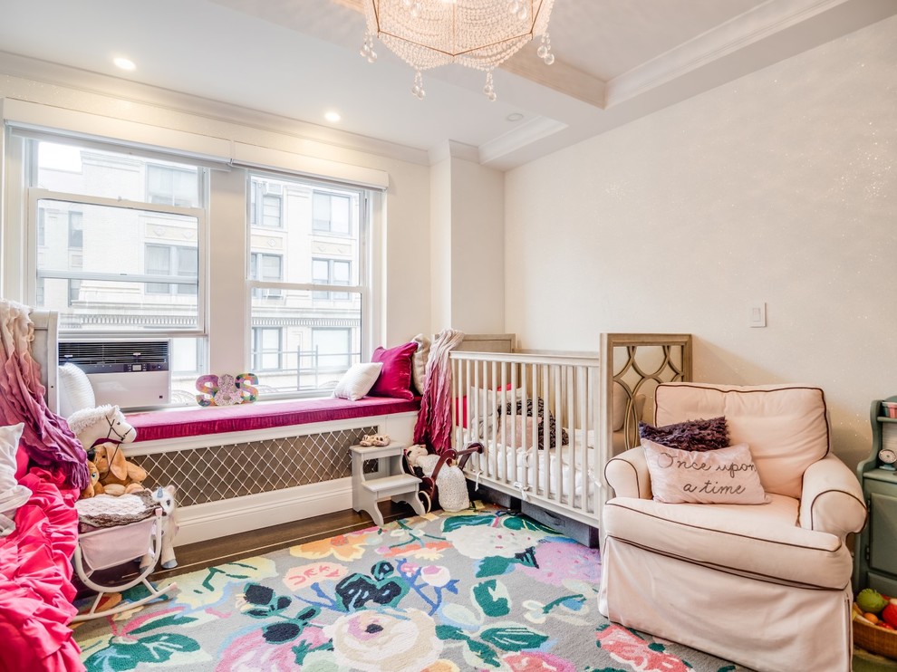 This is an example of a mid-sized transitional nursery for girls in New York with white walls, dark hardwood floors and brown floor.