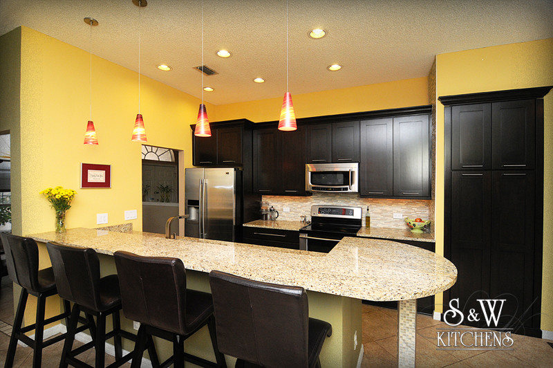 Transitional kitchen photo in Orlando with a single-bowl sink, shaker cabinets, dark wood cabinets, granite countertops, beige backsplash, mosaic tile backsplash and stainless steel appliances