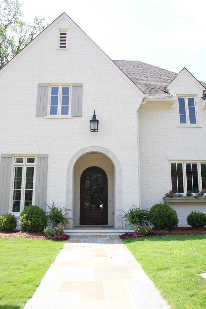 Large transitional two-storey brick white house exterior in Birmingham with a hip roof and a shingle roof.