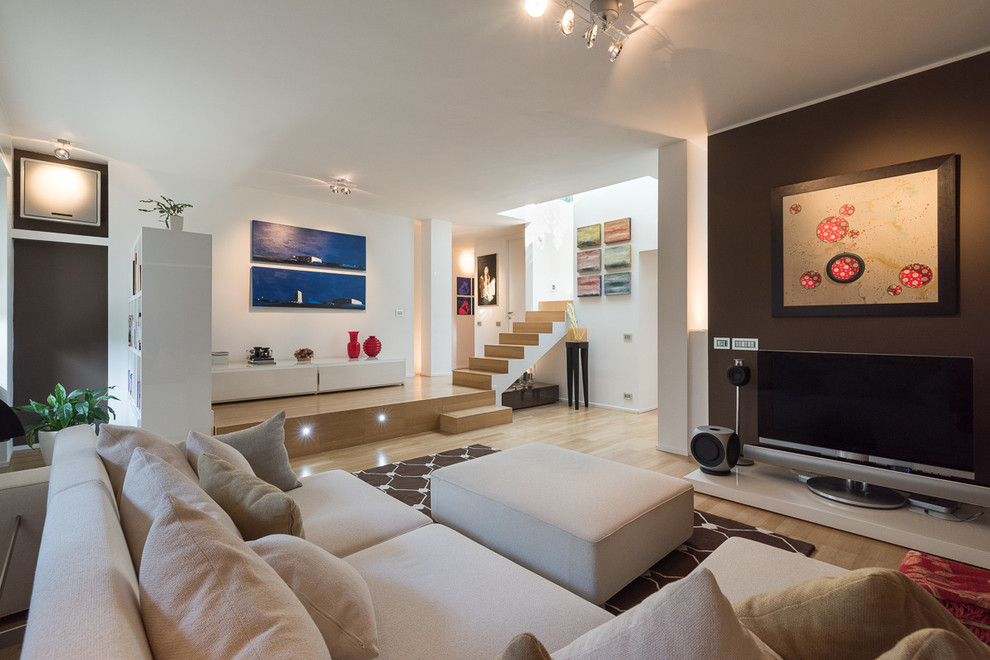 Large contemporary open concept living room in Milan with a music area, multi-coloured walls, light hardwood floors and a freestanding tv.