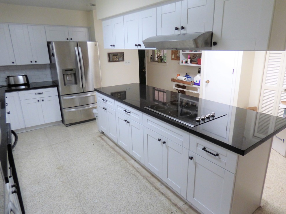 This is an example of a mid-sized contemporary u-shaped eat-in kitchen in Houston with a drop-in sink, recessed-panel cabinets, white cabinets, granite benchtops, white splashback, ceramic splashback, stainless steel appliances, terrazzo floors, with island, beige floor and white benchtop.