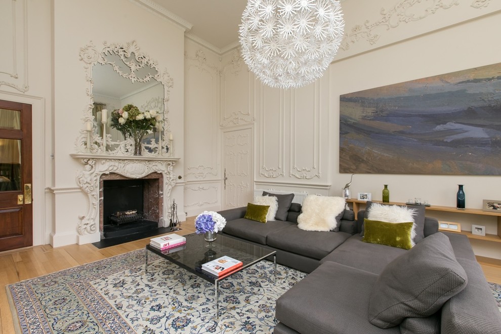 This is an example of a medium sized eclectic formal enclosed living room in Other with white walls, light hardwood flooring, a standard fireplace and a plastered fireplace surround.