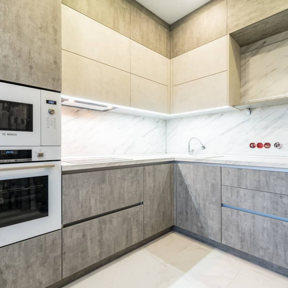 Mid-sized urban l-shaped porcelain tile and white floor eat-in kitchen photo in Moscow with a drop-in sink, recessed-panel cabinets, stainless steel cabinets, solid surface countertops, white backsplash, granite backsplash, stainless steel appliances, no island and white countertops