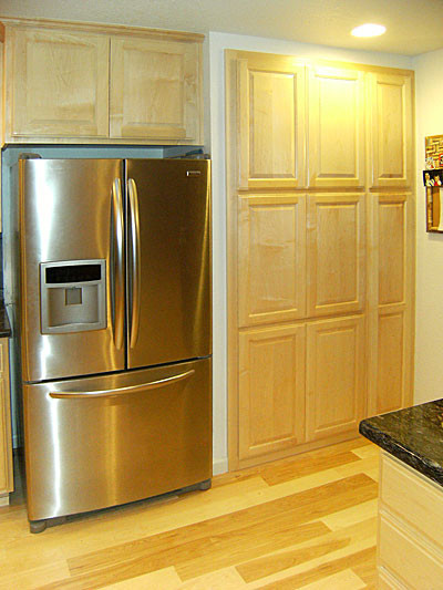 Example of a brown floor kitchen design with raised-panel cabinets and stainless steel appliances