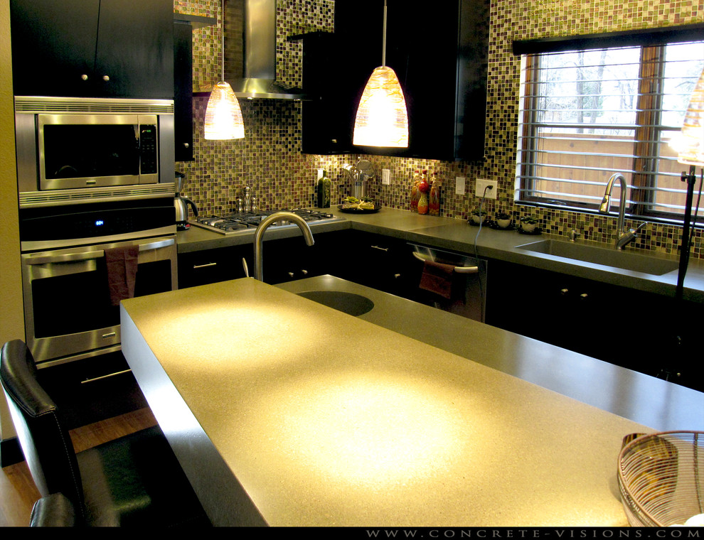 Пример оригинального дизайна: угловая кухня-гостиная в современном стиле с монолитной мойкой, плоскими фасадами, черными фасадами, столешницей из бетона, разноцветным фартуком, фартуком из стеклянной плитки и полом из бамбука