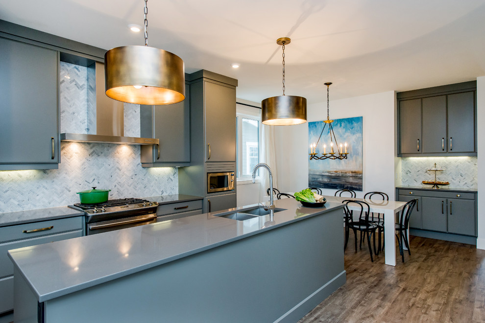Inspiration for a mid-sized transitional dark wood floor eat-in kitchen remodel in Calgary with an undermount sink, flat-panel cabinets, gray cabinets, quartz countertops, multicolored backsplash, mosaic tile backsplash, stainless steel appliances and an island
