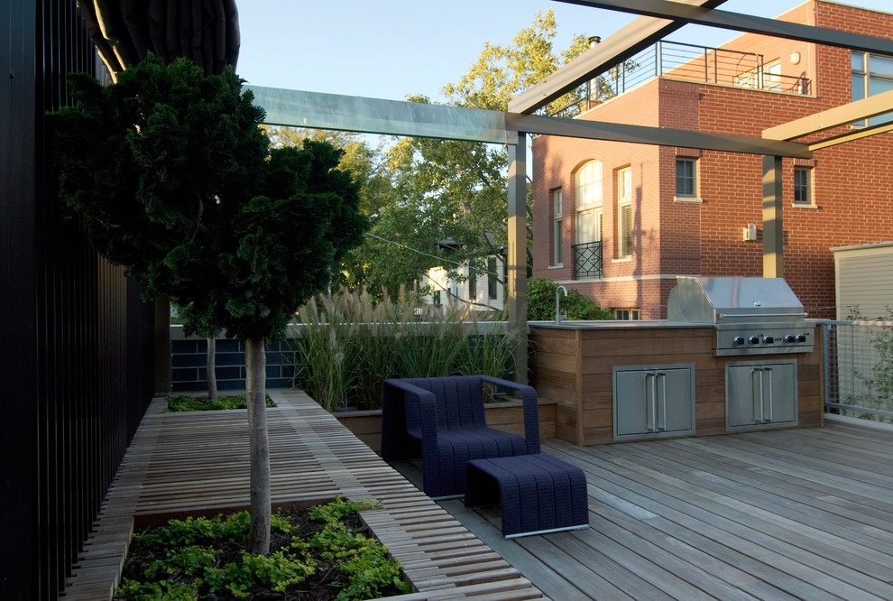 This is an example of a large modern rooftop deck in Chicago with an outdoor kitchen and an awning.