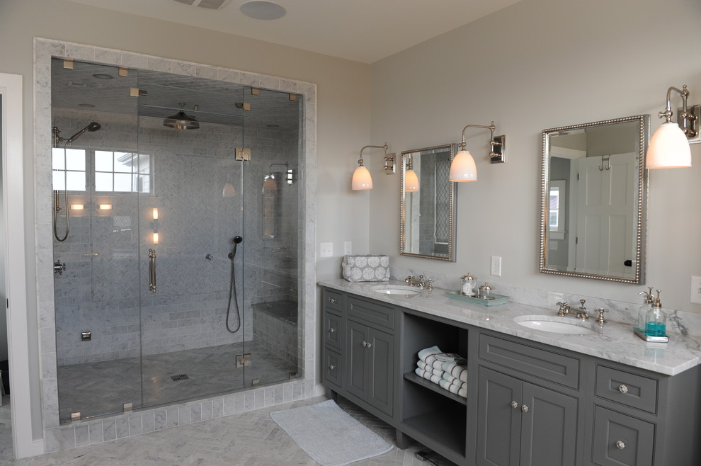 Photo of a large transitional master bathroom in New York with grey cabinets, gray tile, beige walls, an undermount sink, an alcove shower, marble floors, grey floor, a hinged shower door, beaded inset cabinets, a freestanding tub, marble and marble benchtops.