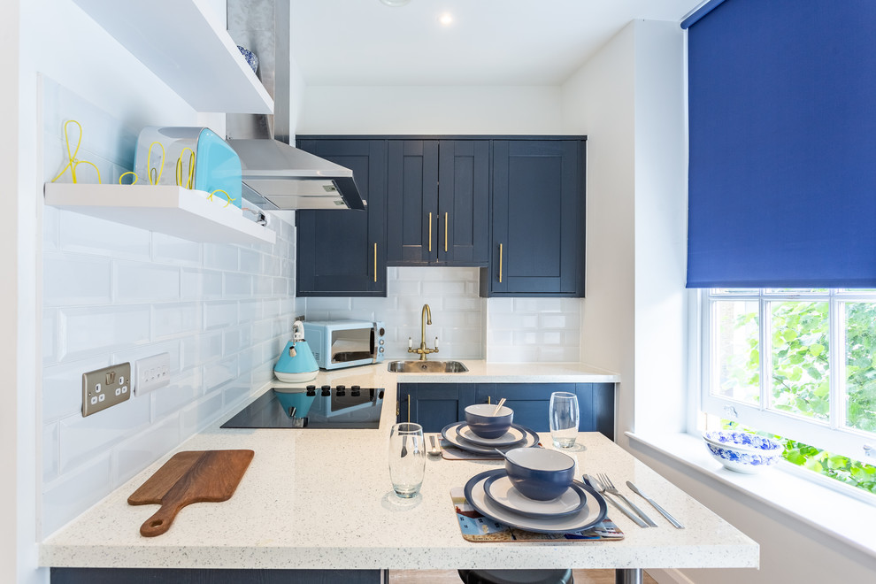Inspiration for a contemporary u-shaped kitchen in Los Angeles with a drop-in sink, shaker cabinets, blue cabinets, subway tile splashback, stainless steel appliances, a peninsula and white benchtop.