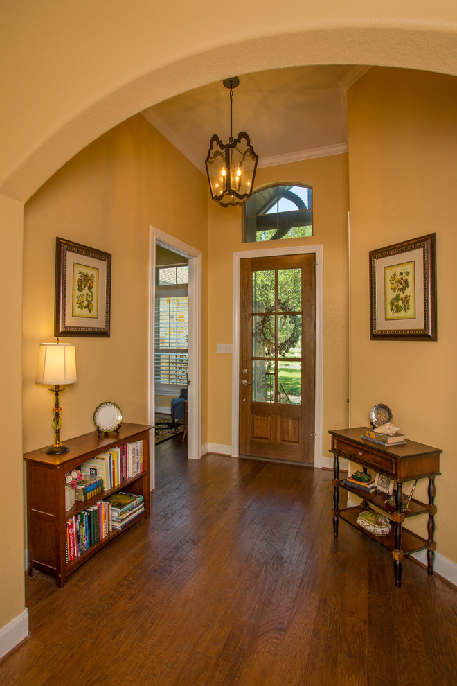 Inspiration for a mid-sized transitional foyer in Austin with yellow walls, medium hardwood floors, a single front door and a medium wood front door.