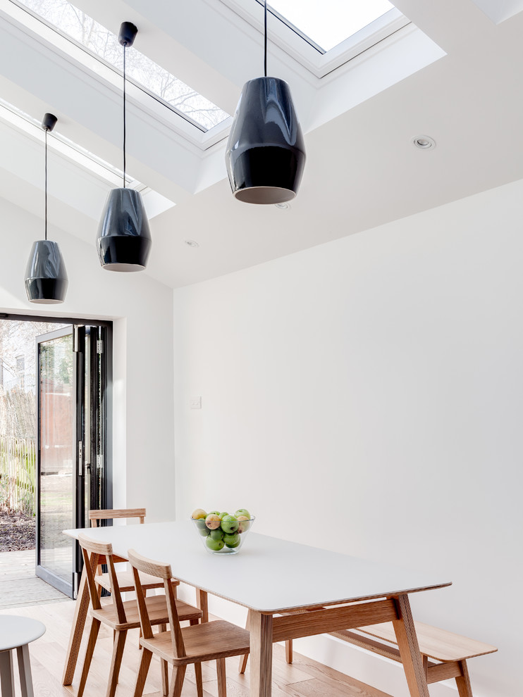 Inspiration for a mid-sized contemporary kitchen/dining combo in London with white walls and light hardwood floors.