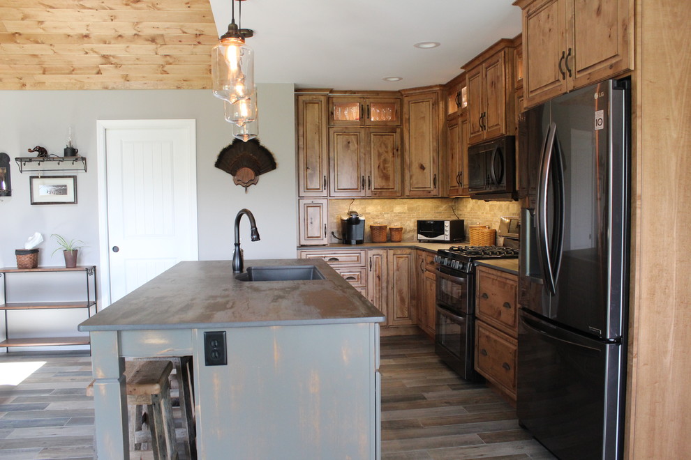 Inspiration for a mid-sized rustic l-shaped ceramic tile and multicolored floor eat-in kitchen remodel in Philadelphia with an undermount sink, raised-panel cabinets, medium tone wood cabinets, stone tile backsplash, black appliances, an island, stainless steel countertops and beige backsplash