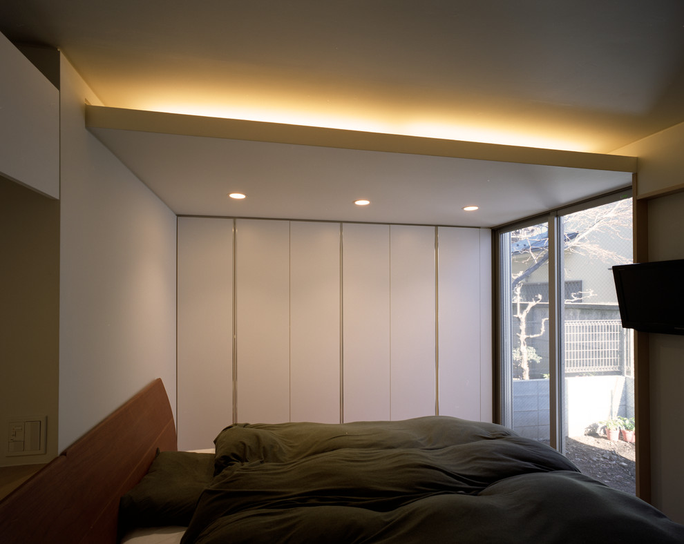 Ejemplo de dormitorio minimalista pequeño sin chimenea con paredes blancas, suelo de madera clara, marco de chimenea de yeso y suelo beige