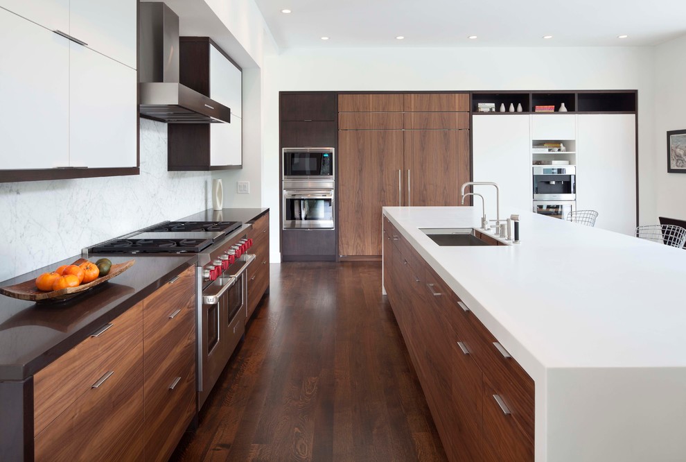 Contemporary l-shaped open plan kitchen in Minneapolis with an undermount sink, flat-panel cabinets, solid surface benchtops, white splashback, stone slab splashback and stainless steel appliances.