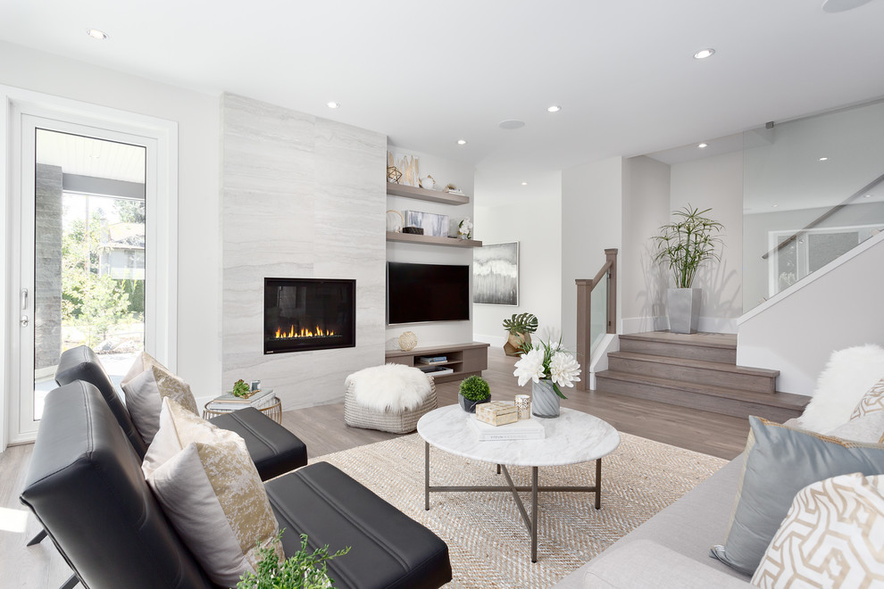 Design ideas for a mid-sized contemporary formal open concept living room in Vancouver with grey walls, a wall-mounted tv, medium hardwood floors, a standard fireplace, a stone fireplace surround and brown floor.