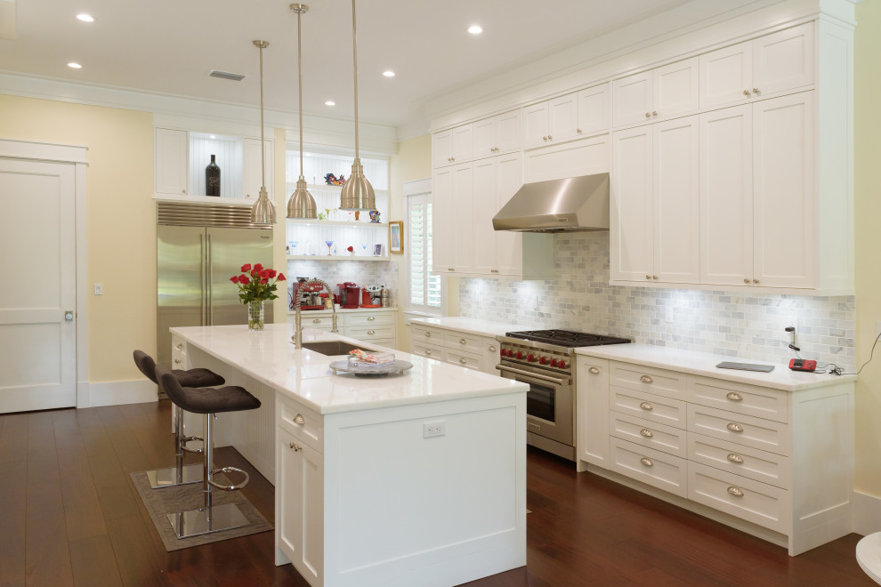 Inspiration for a mid-sized transitional u-shaped kitchen in Miami with an undermount sink, shaker cabinets, white cabinets, quartz benchtops, grey splashback, subway tile splashback, stainless steel appliances, medium hardwood floors, with island, brown floor and white benchtop.