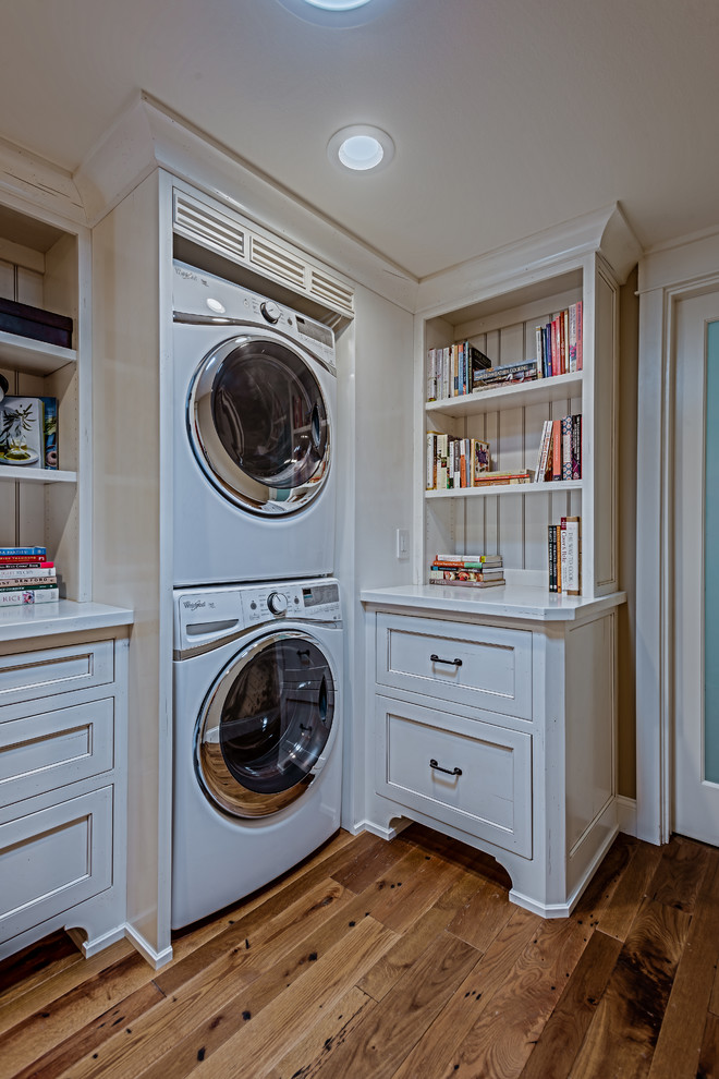 This is an example of a small country l-shaped laundry room in Orange County with shaker cabinets, wood benchtops, light hardwood floors and a side-by-side washer and dryer.