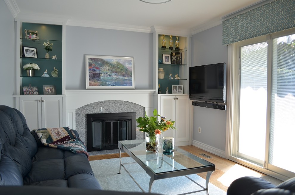 Design ideas for a mid-sized transitional enclosed family room in Toronto with grey walls, light hardwood floors, a standard fireplace, a stone fireplace surround and a wall-mounted tv.