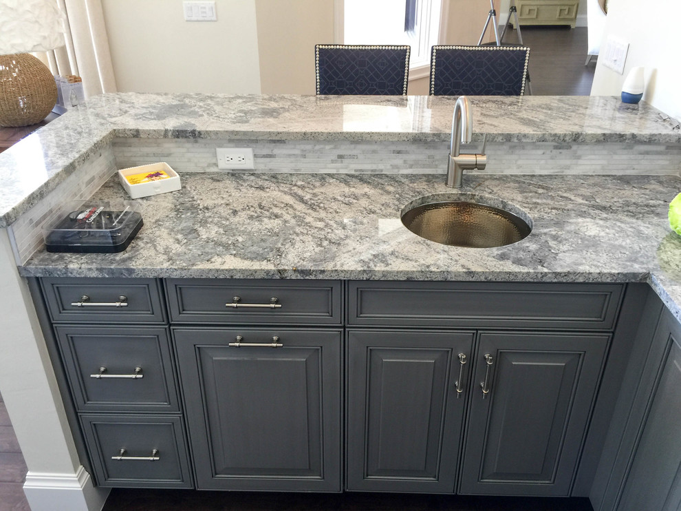 This is an example of a mid-sized transitional u-shaped seated home bar in Miami with an undermount sink, blue cabinets, granite benchtops, grey splashback, stone tile splashback and dark hardwood floors.