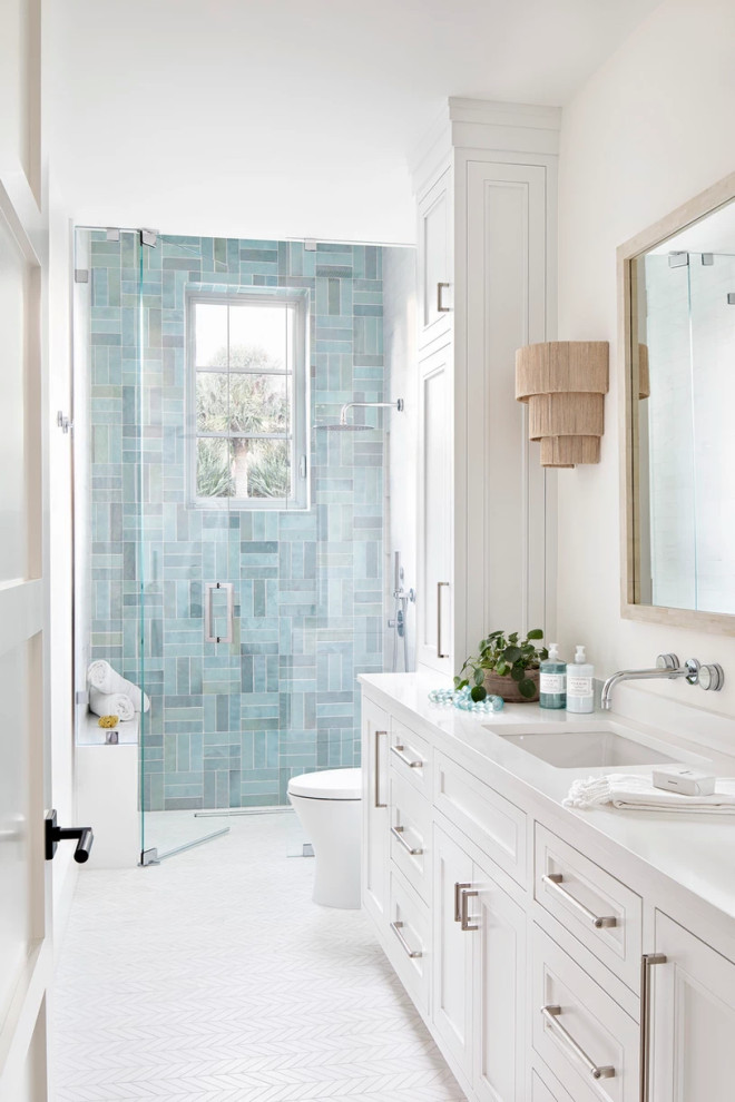 This is an example of a beach style bathroom in Miami with shaker cabinets, white cabinets, a curbless shower, blue tile, white walls, mosaic tile floors, an undermount sink, white floor, a hinged shower door, white benchtops, a shower seat and a built-in vanity.