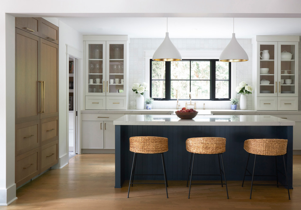 Inspiration for a large transitional u-shaped open plan kitchen in Chicago with a farmhouse sink, shaker cabinets, white cabinets, quartz benchtops, white splashback, panelled appliances, medium hardwood floors, with island, brown floor, multi-coloured benchtop and exposed beam.