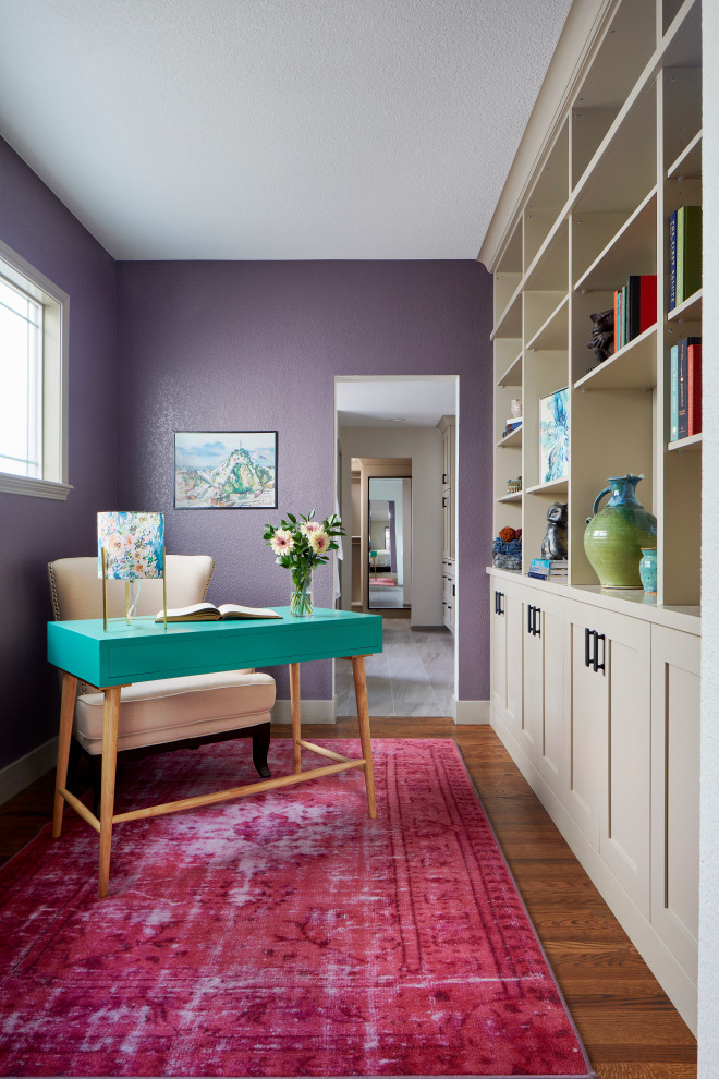 This is an example of a transitional study room in Denver with purple walls, dark hardwood floors, a freestanding desk and brown floor.