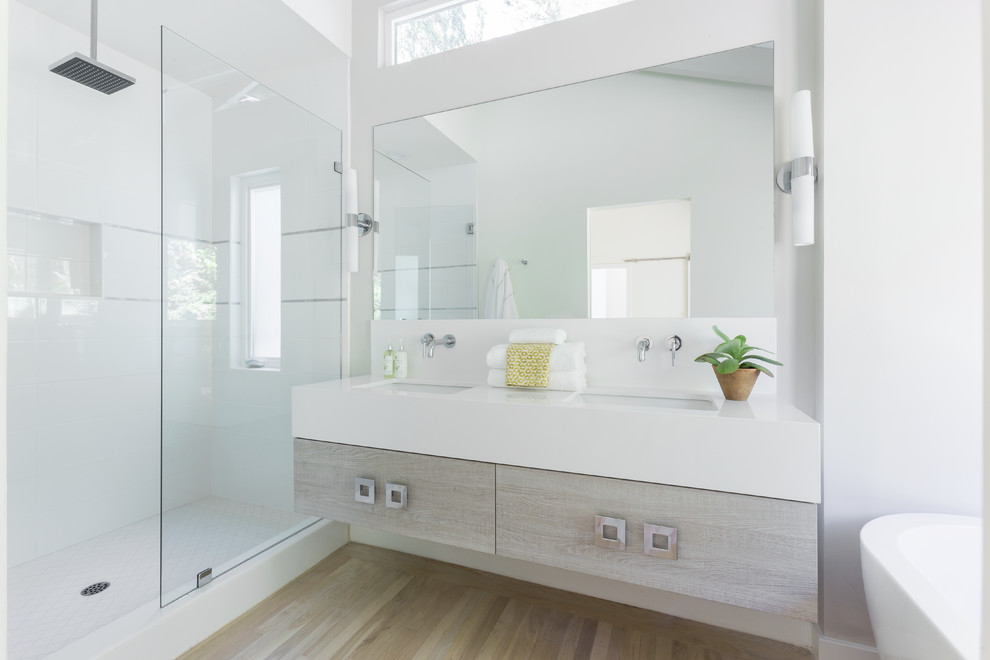 This is an example of a mid-sized beach style master bathroom in Boston with flat-panel cabinets, a freestanding tub, white tile, ceramic tile, white walls, light hardwood floors, an undermount sink, quartzite benchtops, white benchtops, medium wood cabinets, an alcove shower, a hinged shower door, a double vanity, a floating vanity, a two-piece toilet, beige floor, an enclosed toilet and vaulted.